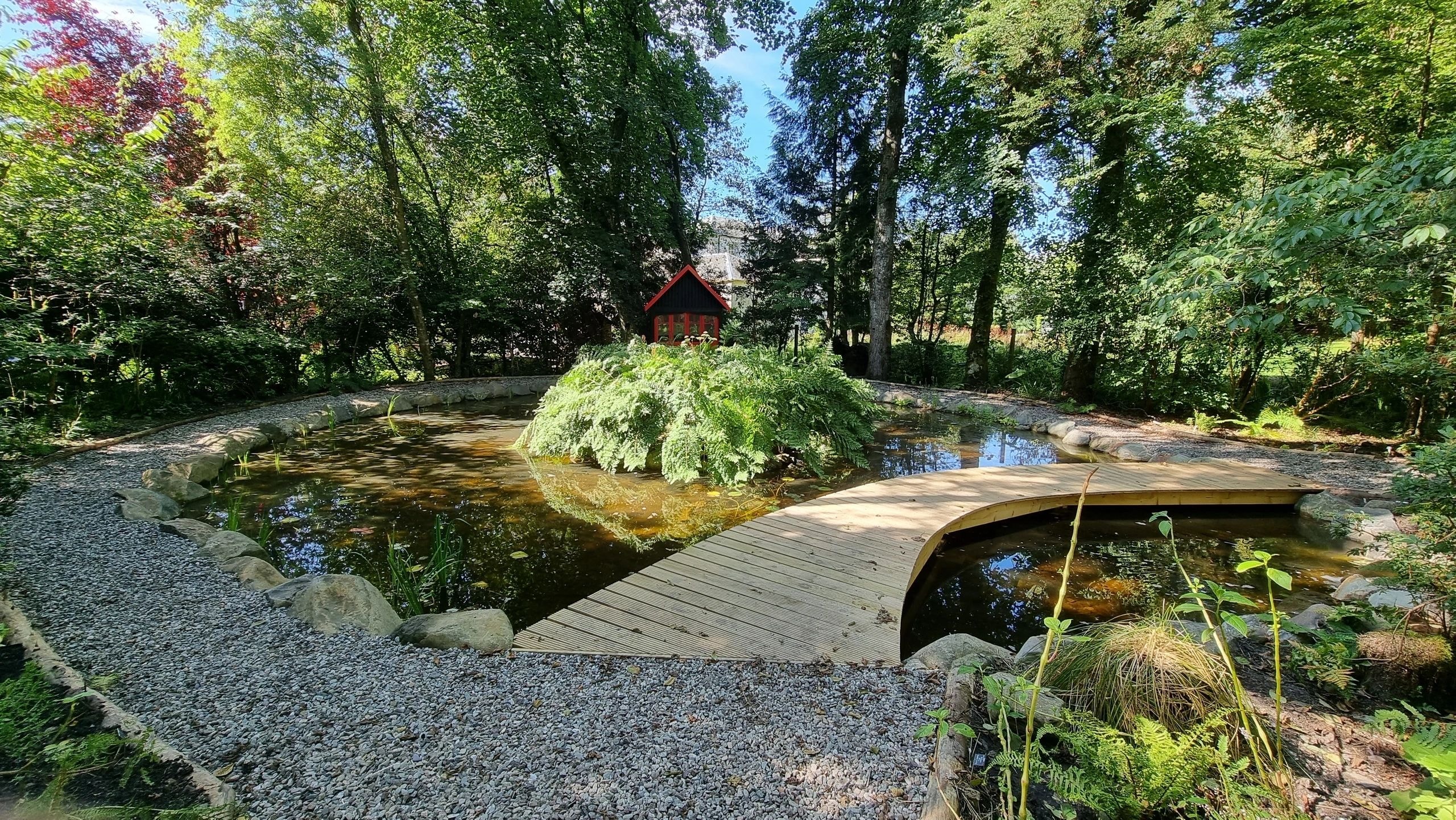 Wooden bridge crossing garden pond in forest setting